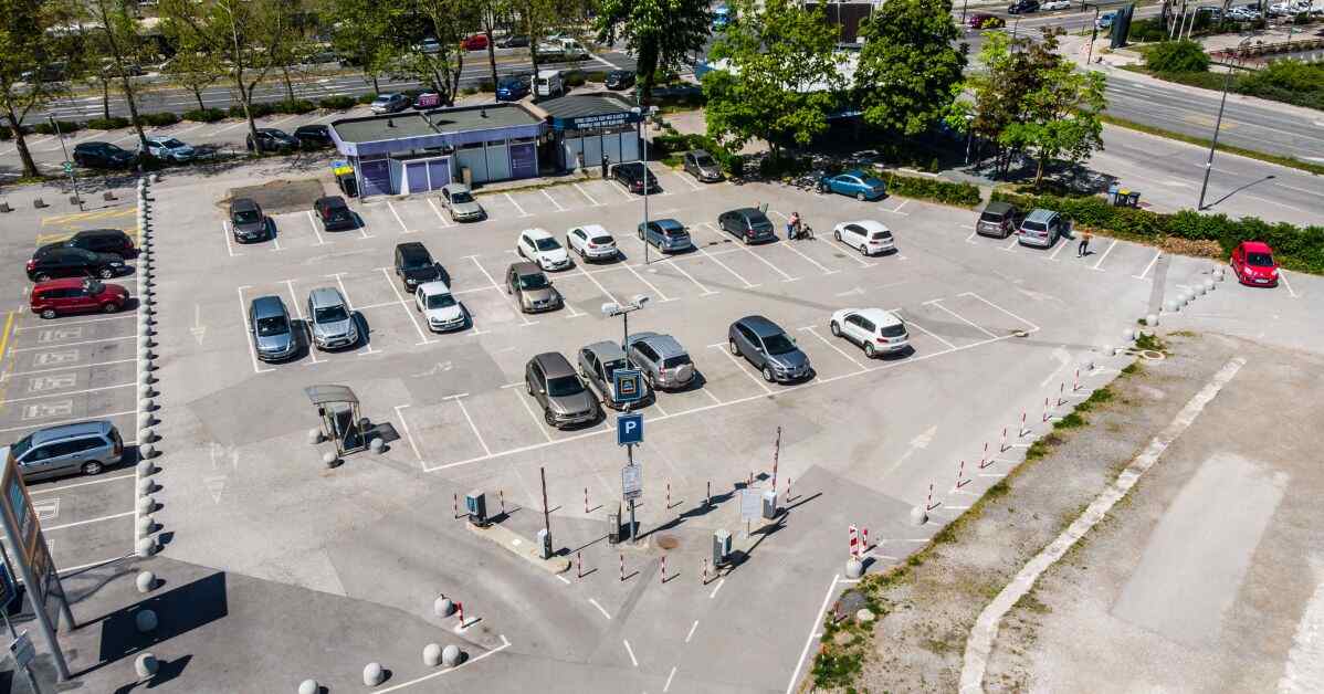 Aerial view of the outdoor Linhartova parking lot (Parkirišče Linhartova) with cars parked in designated bays next to Linhartova cesta in Ljubljana, Slovenia.