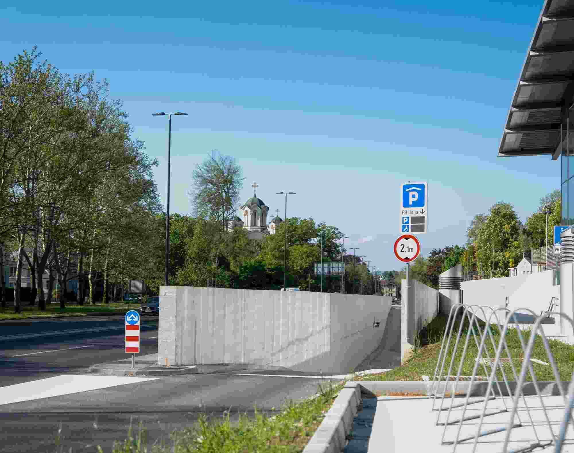 Entrance ramp to the modern underground Ilirija parking garage (PH Ilirija) along Celovska cesta in Ljubljana, Slovenia.